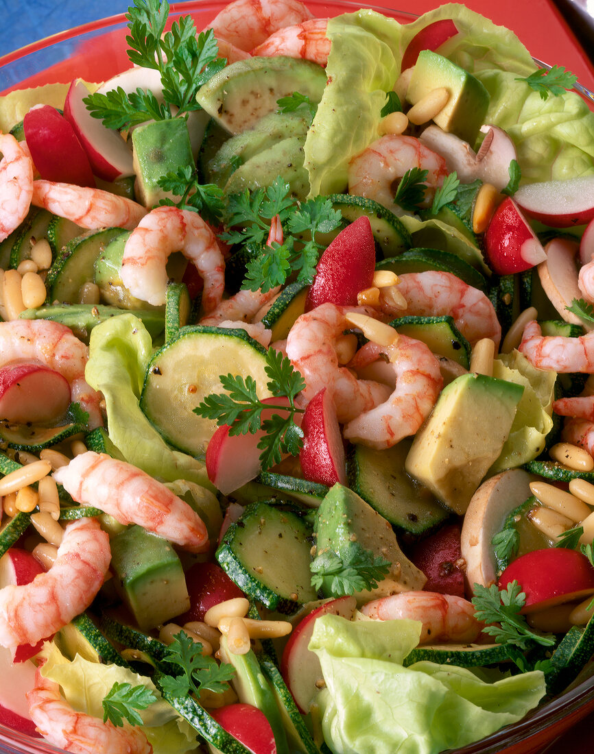 Close-up of shrimp salad with avocados, zucchini, radishes, mushrooms and pine nuts