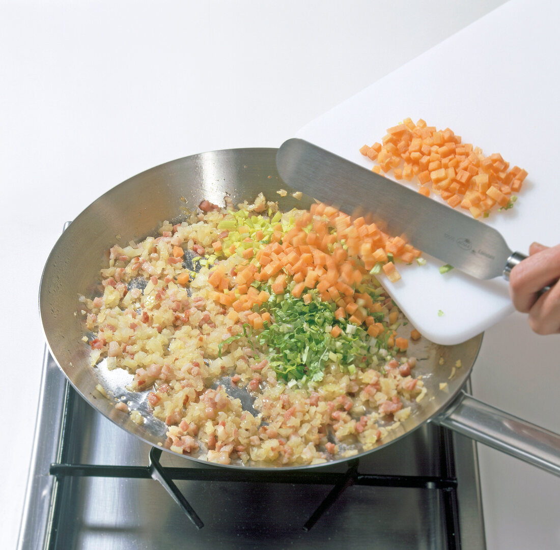 Vegetables being added in frying pan while preparing partridge pie, step 4