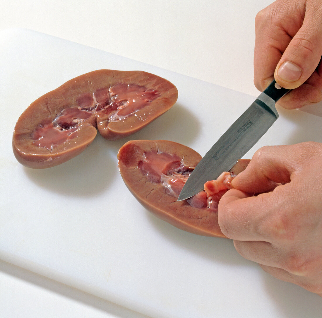 Close-up of hands slicing wild boar kidneys, step 2