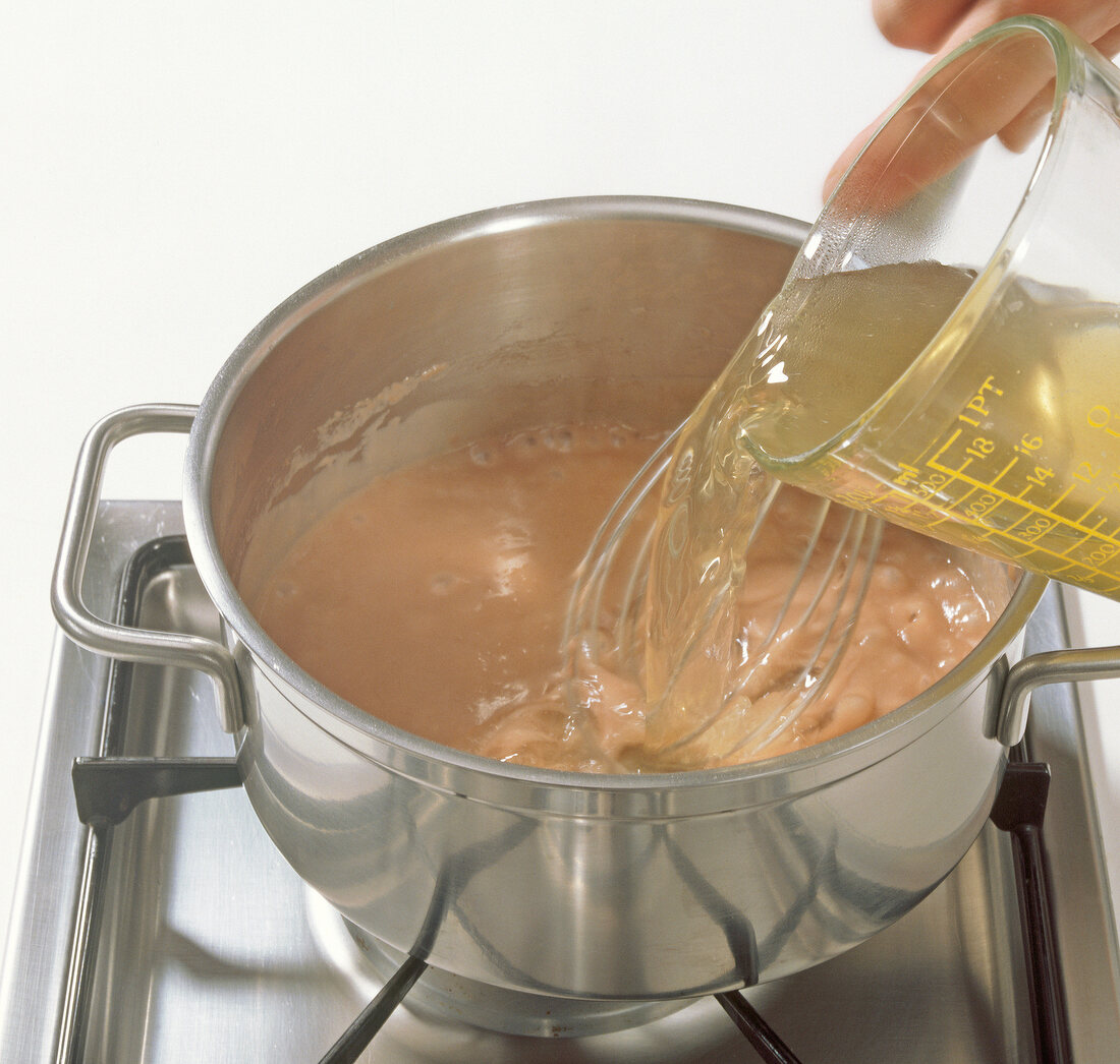 Adding juice to dark sauce in pot for preparation of beuschel, step 2