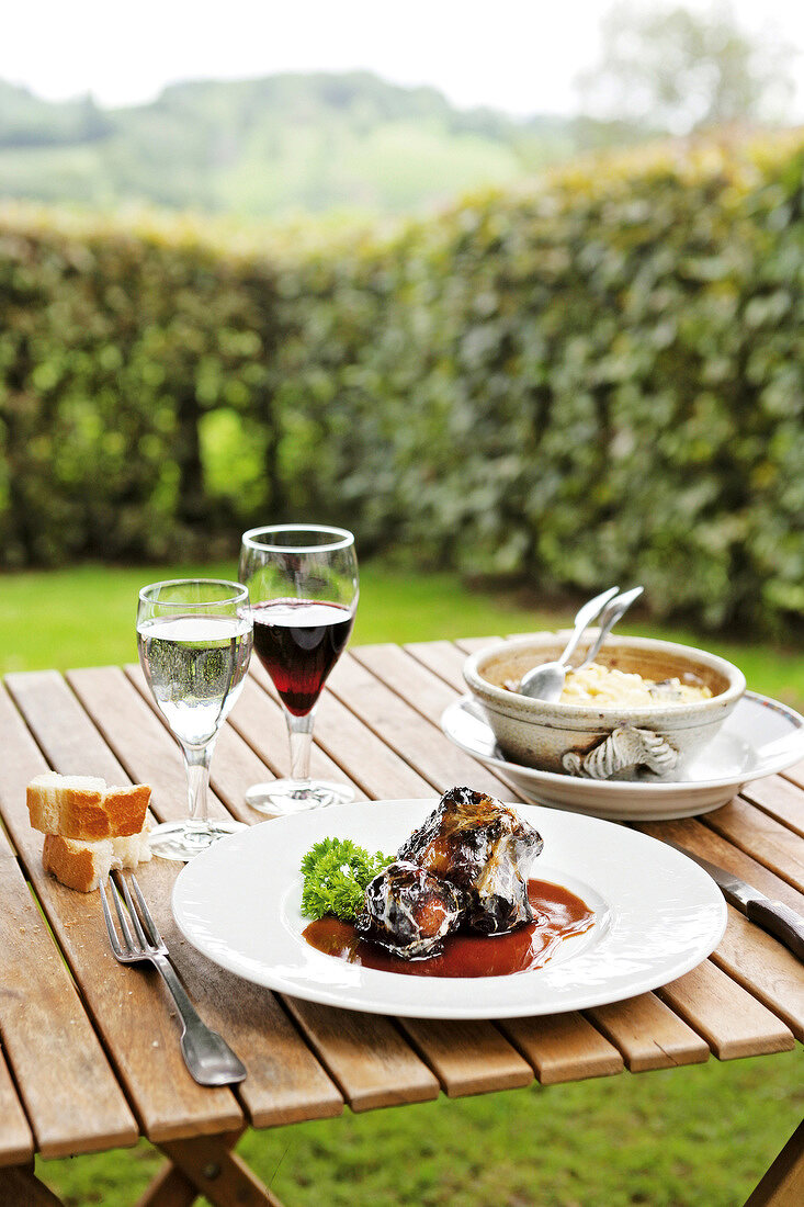 Laid table with oxtail on plate beside glass of wine in Ferme-Auberge du Bruel, France