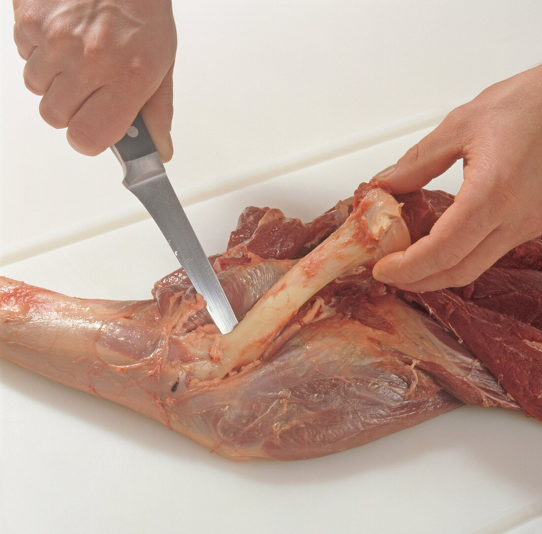 Close-up of deboning venison by knife for preparation of braised venison, step 3