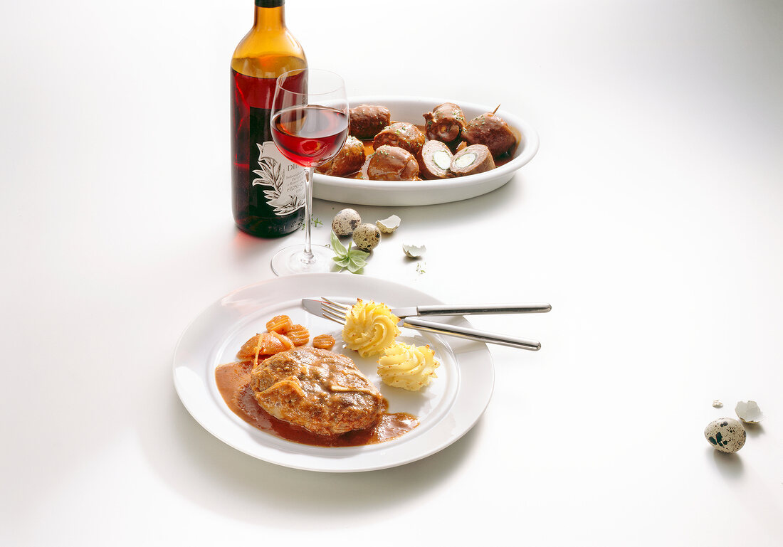 Osso buco and deer roulades with quail eggs and red wine on white background