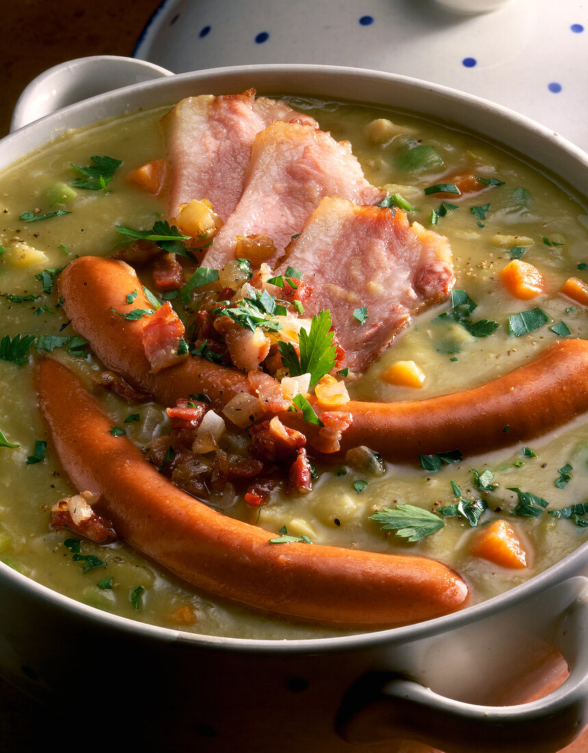 Close-up of pea soup with pig's cheek and sausage in serving dish