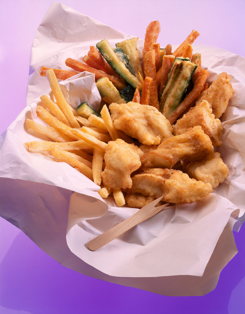 Close-up of fries, fried vegetables and fish on tissue