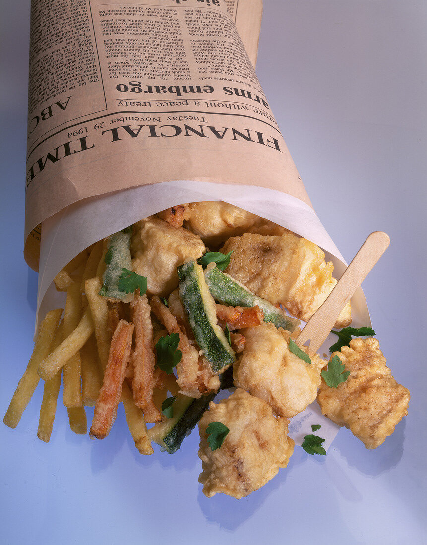 Close-up of fish and French fries wrapped in news paper