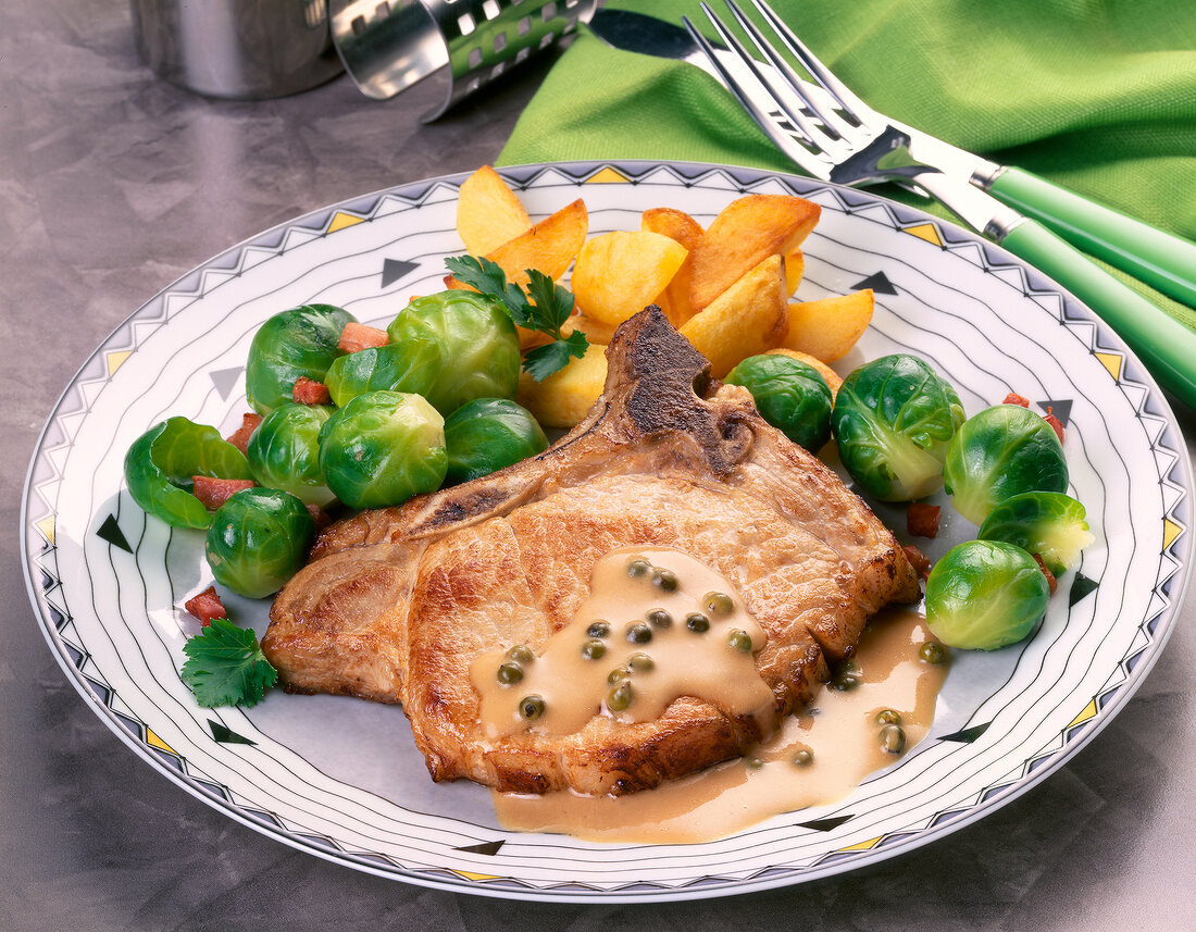 Koteletts mit Pfeffersoße und Rosenkohl, close-up.