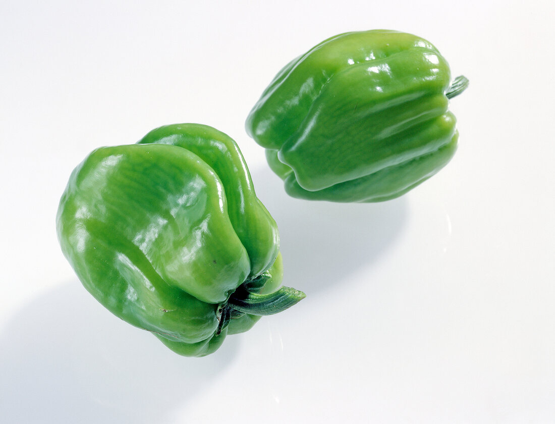 Close-up of two green bell peppers on white background