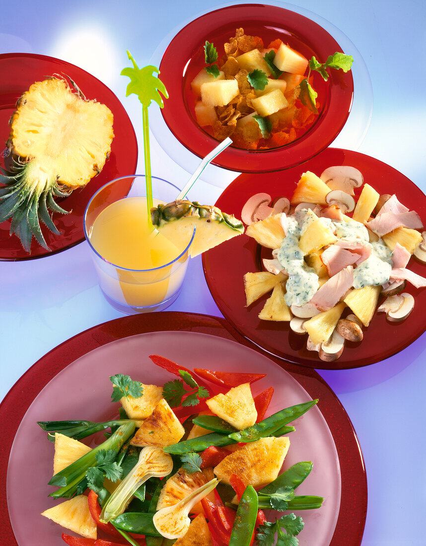 Diverse Ananasgerichte auf roten Tellern, gelb, Diät