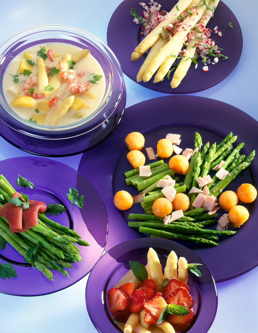 Various asparagus salads on purple plates