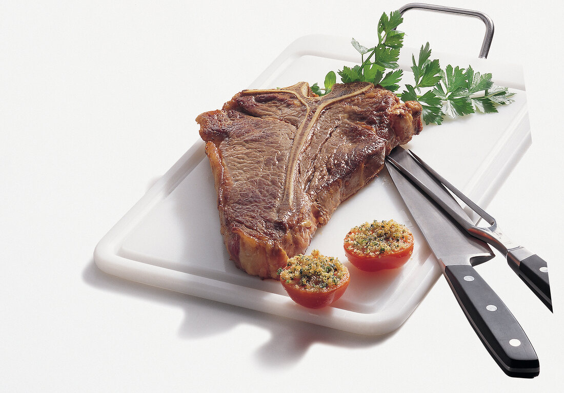 Beef.  T-Bone-Steak und Tomaten auf Brett, Freisteller