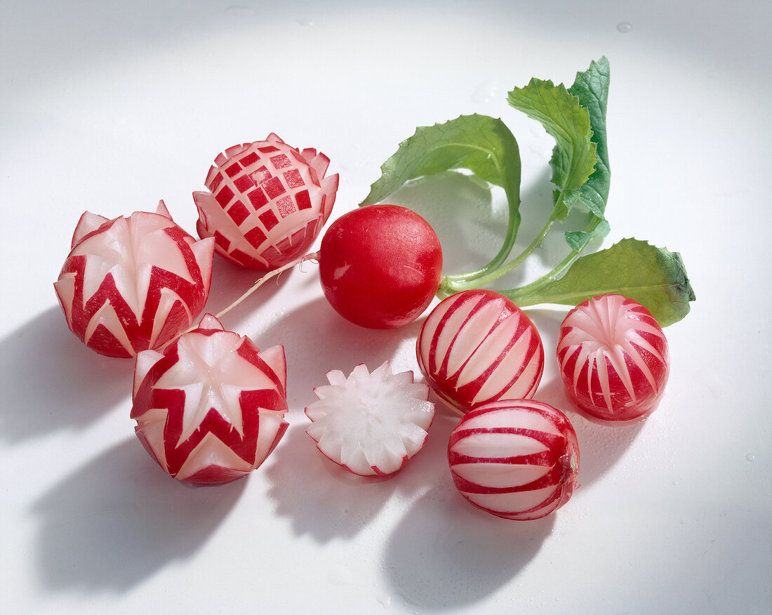Close-up of radishes carved in various designs on white background