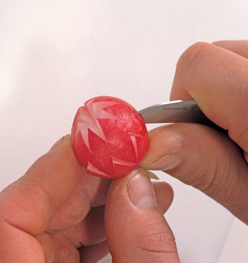 Close-up of radishes notch being carved for decoration, step 2