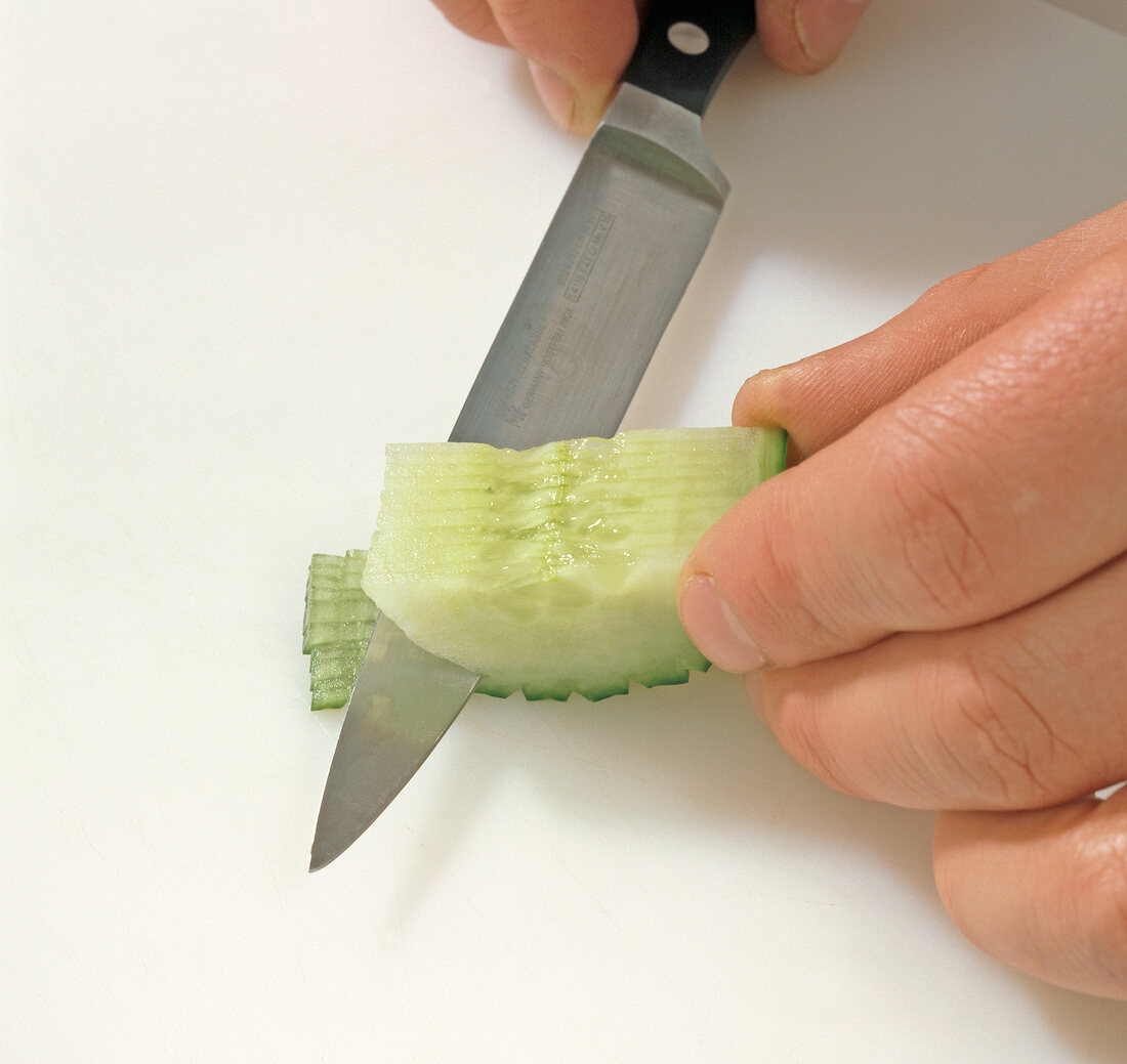 Close-up of cucumber being carved for decoration, step 2