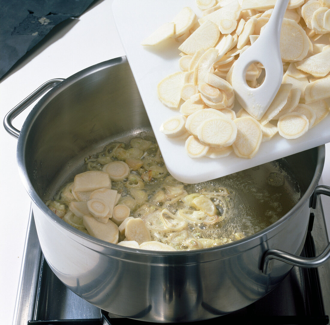 Siler root being added to pot on stove