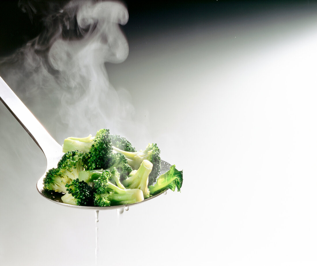 Close-up of hot broccoli florets on a trowel with water dripping down