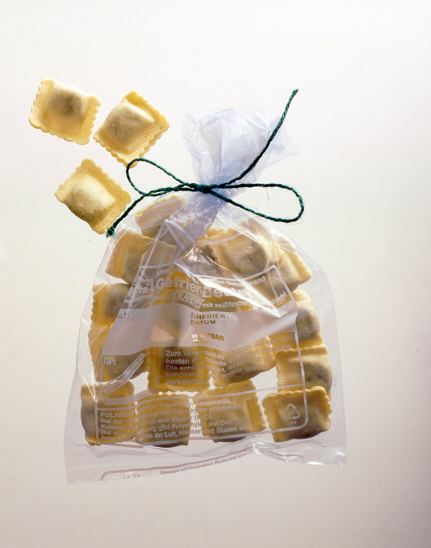 Close-up of freezer bag with ravioli on white background