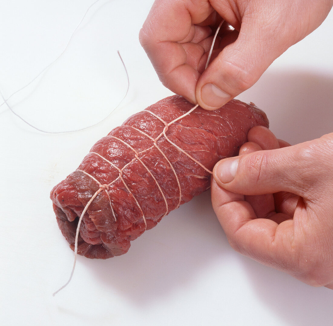 Beef rouladen being tied with yarn for preparation of beef tartare, step 4