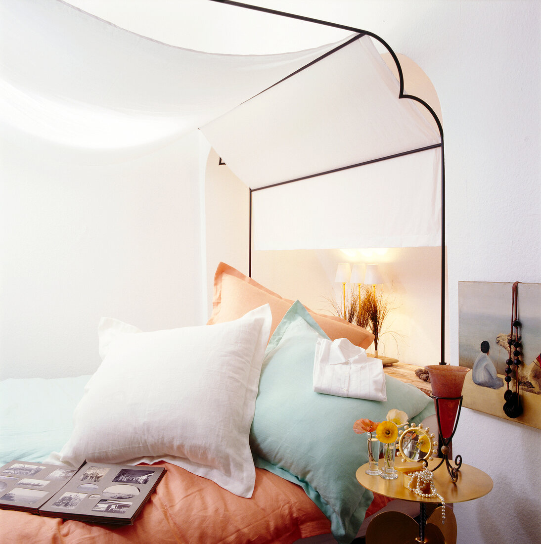 Close-up of white bed with canopy, mint and apricot coloured pillow