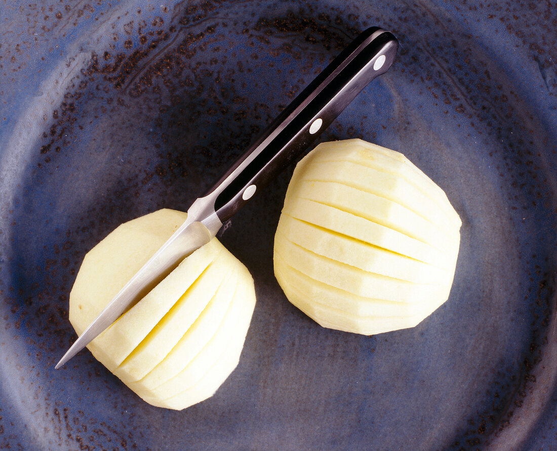 Close-up of two apples cut with knife, overhead view