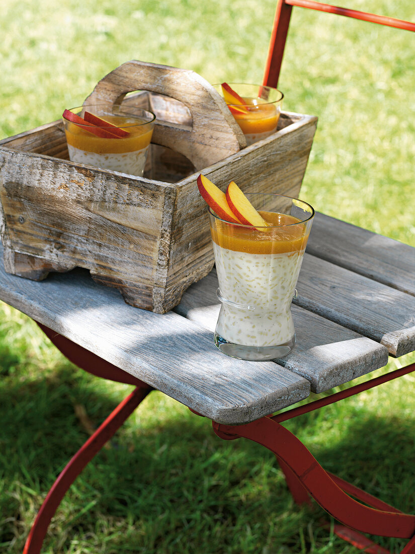 Gläser mit Kokosreis mit Nektarinen stehen auf einem Stuhl