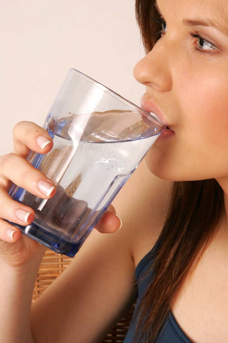 Frau mit langen Haaren trinkt Glas Wasser, Detailaufnahme