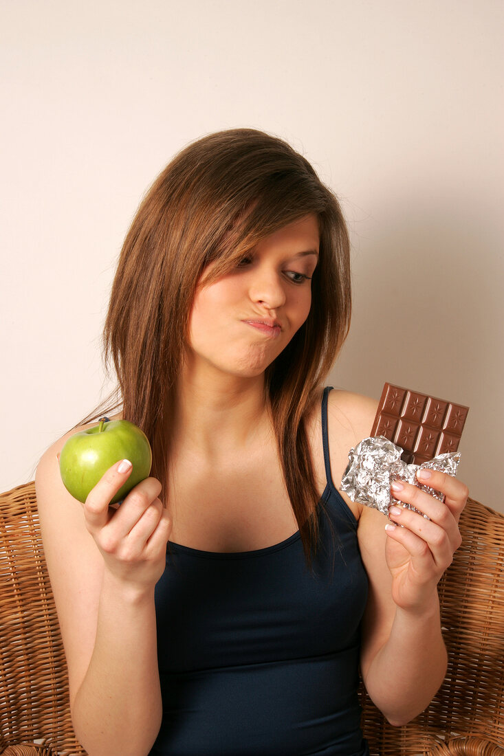Woman with long hair holding green apple and chocolate