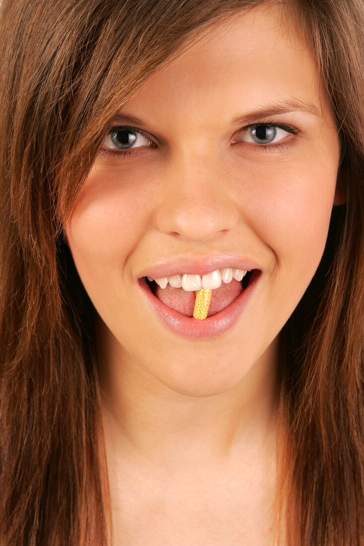 Portrait of gray eyed Magdalena woman holding a capsule in the mouth, close-up