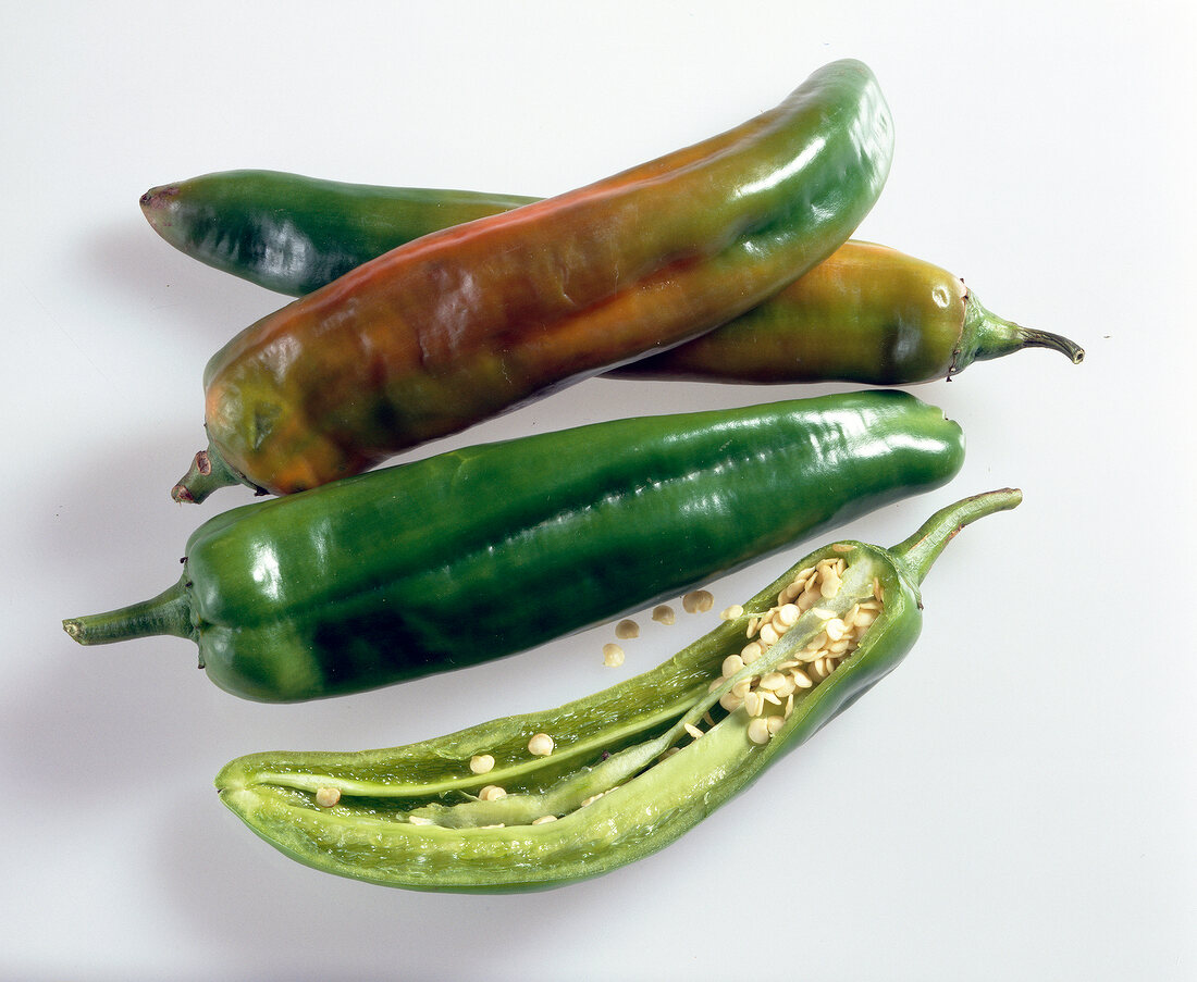 Close-up of three whole and halved chilli de agua on white background