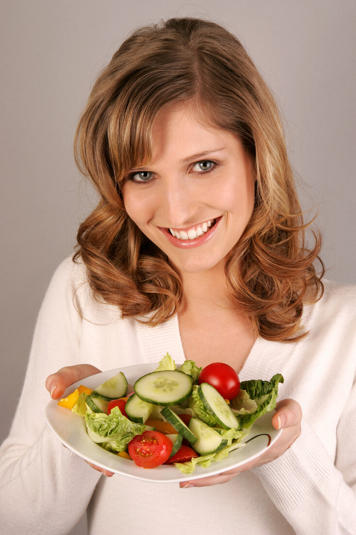 Portrait of beautiful woman holding salad plate and smiling
