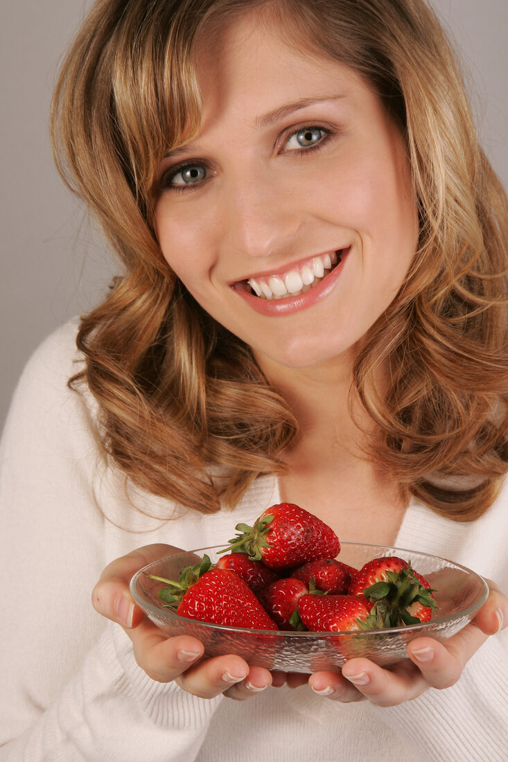 Charlotte Frau mit langen Haaren beisst in eine Erdbeere