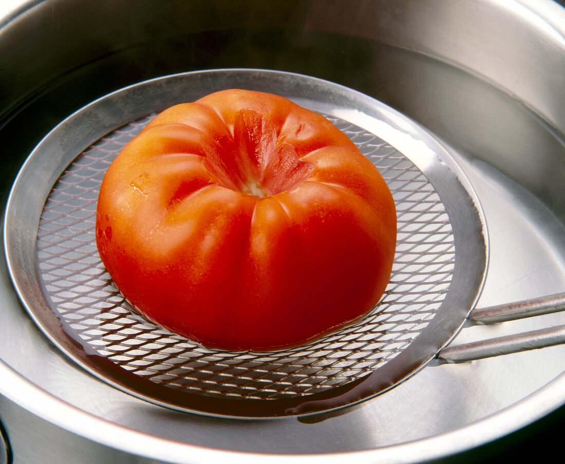 Close-up of tomato on strainer above pot of water
