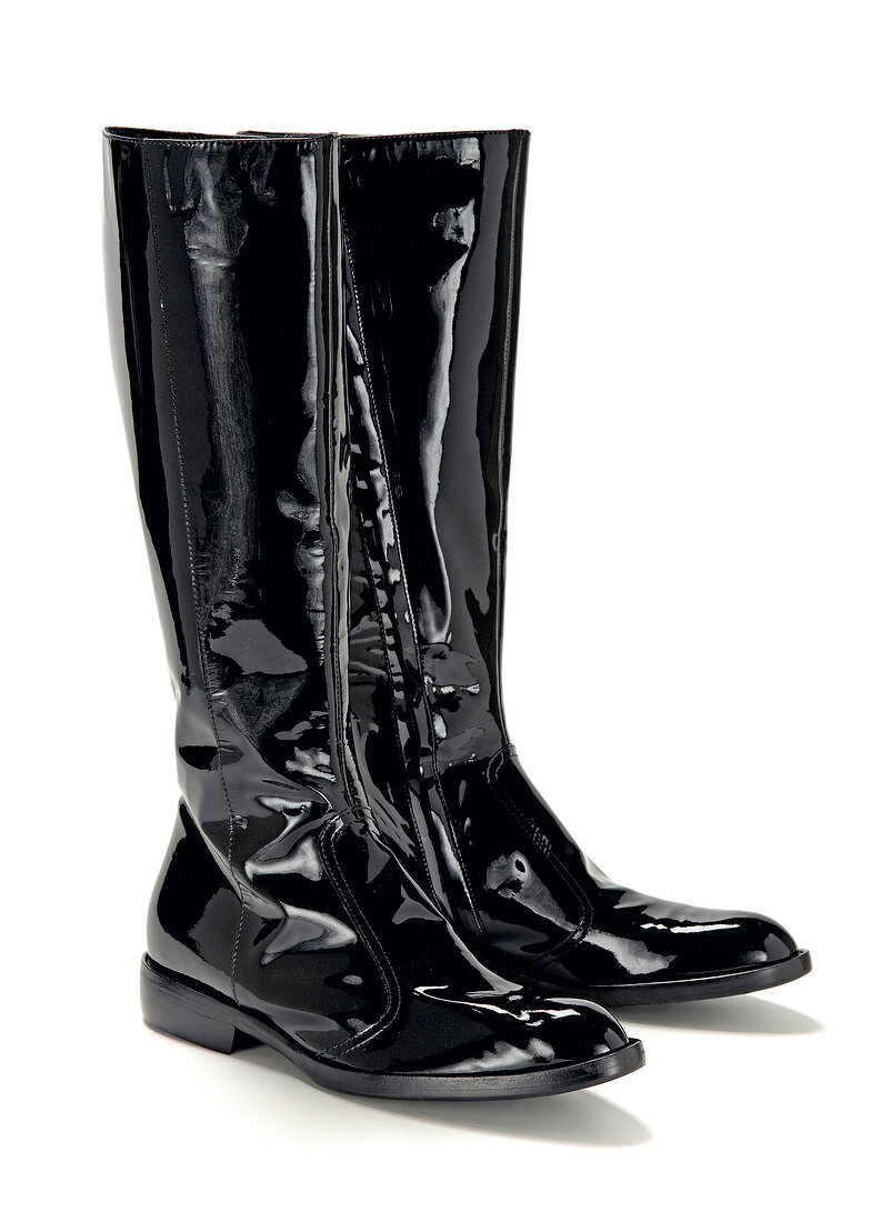 Close-up of black long leather boots on white background