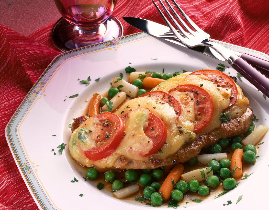 Baked steak with carrots and peas and tomatoes on plate