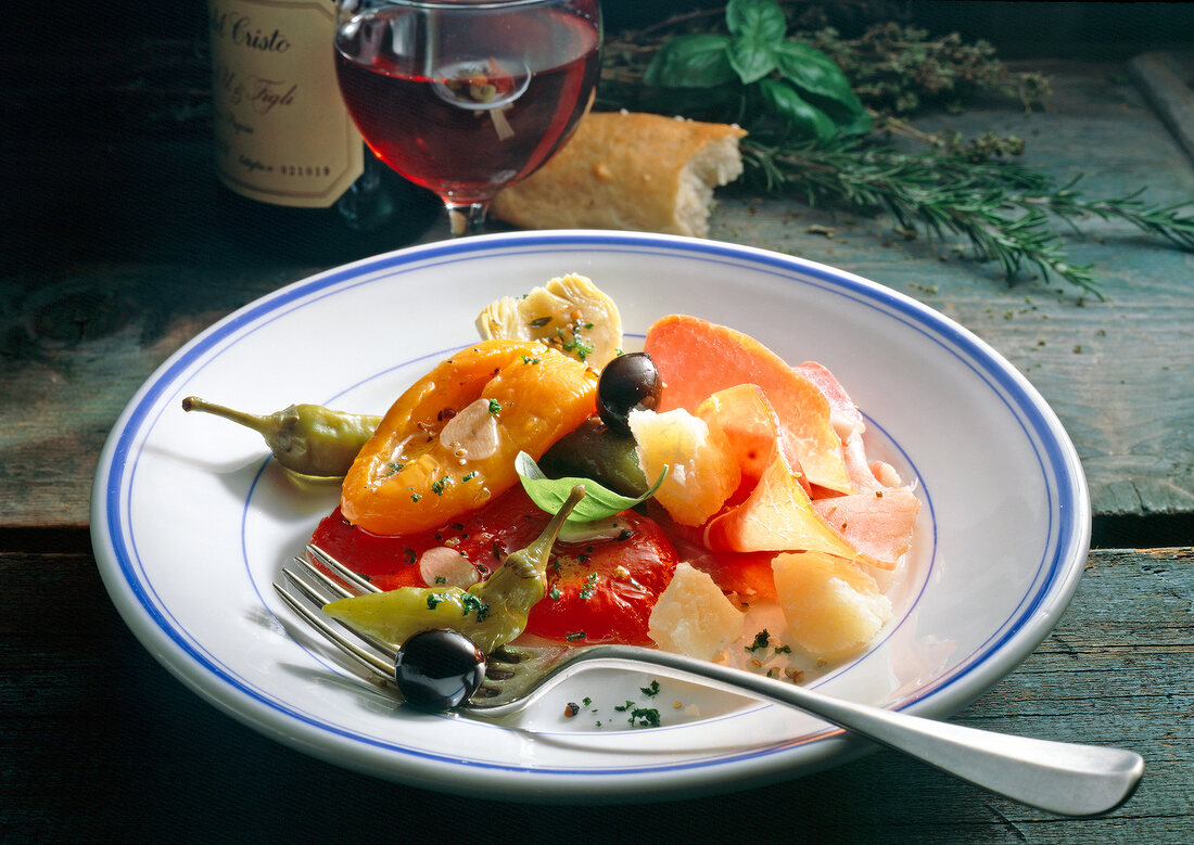 Marinated peppers with ham, olives and chillies on plate