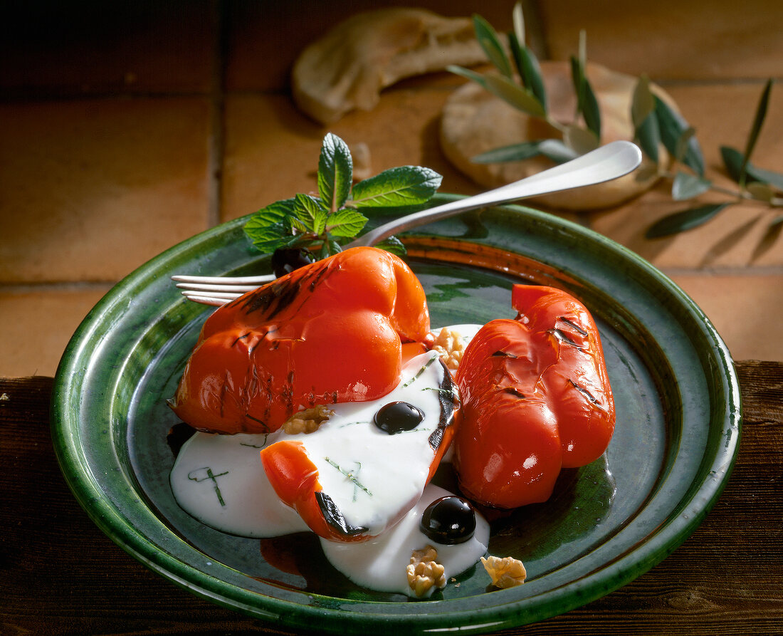 Grilled red peppers with yogurt on green plate