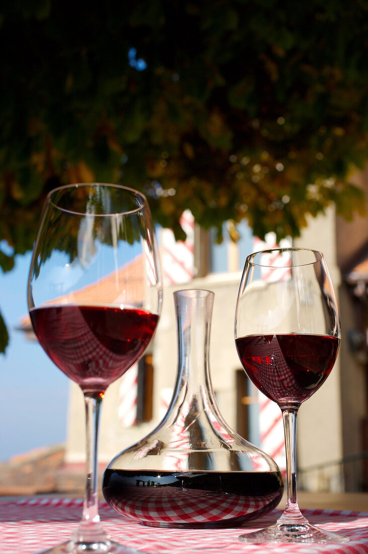 Zwei Gläser Rotwein, dazwischen eine Karaffe mit Rotwein.X