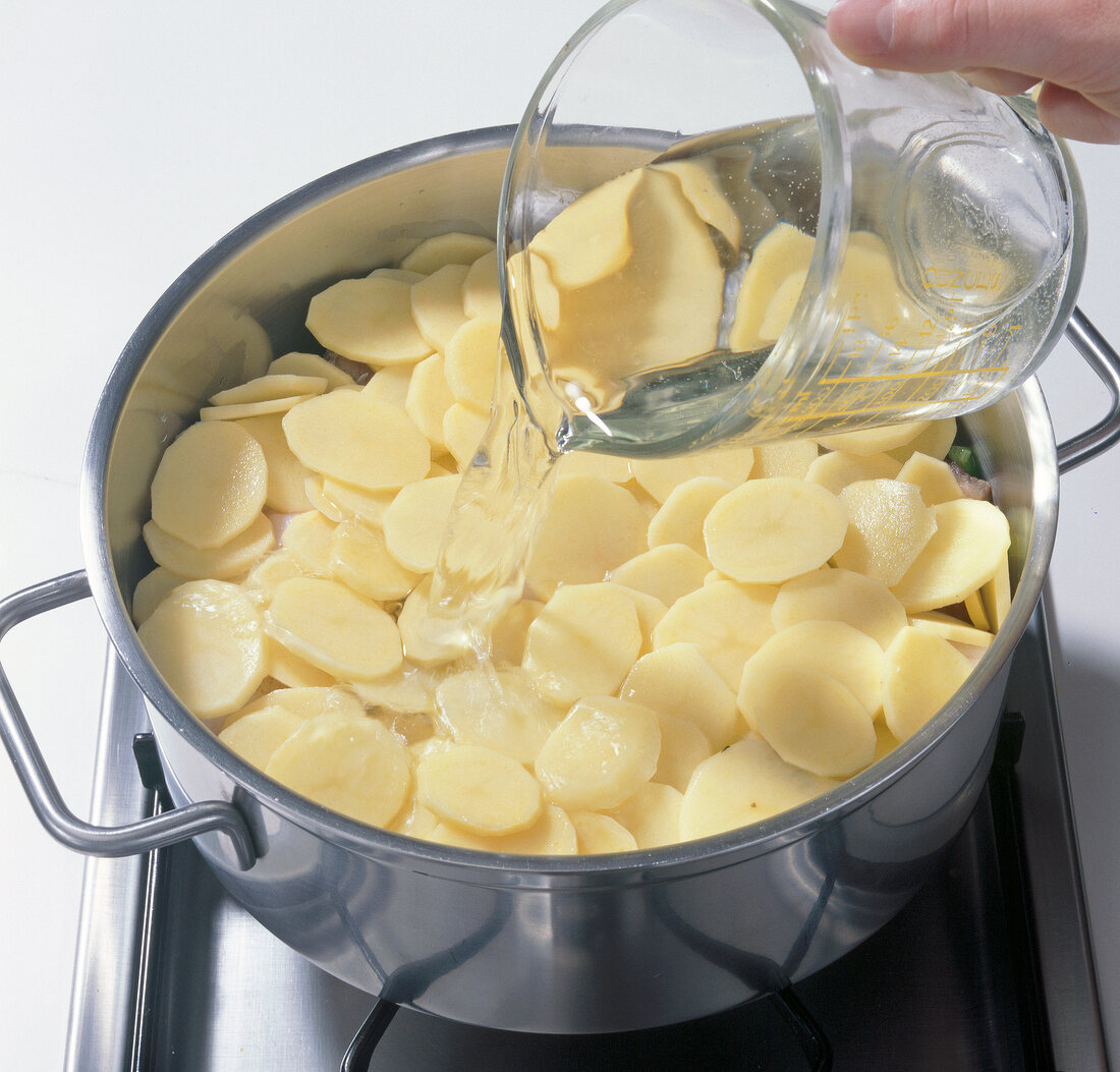 White wine being poured on potatoes in pot, step 4