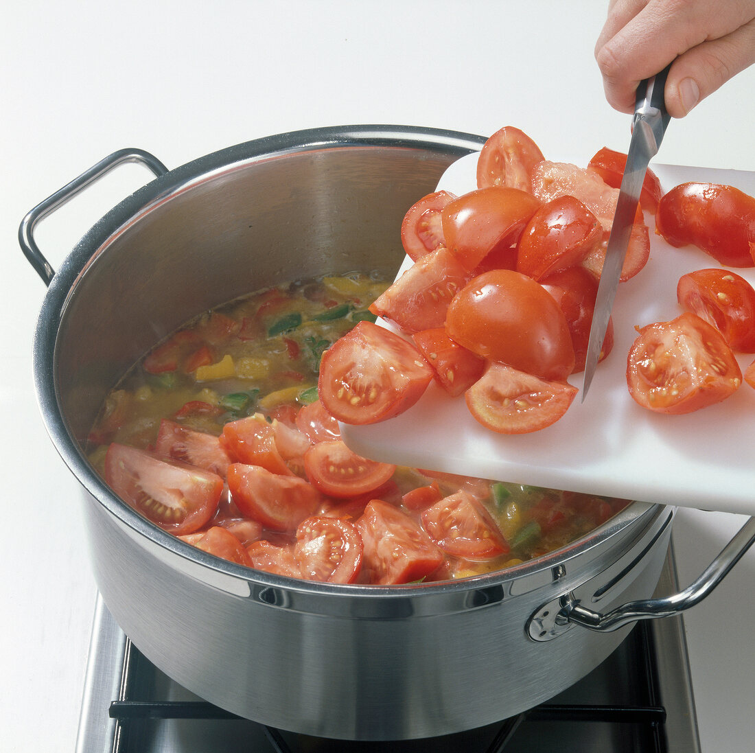 Adding tomatoes to mixture in casserole for preparation of consomme, step 3