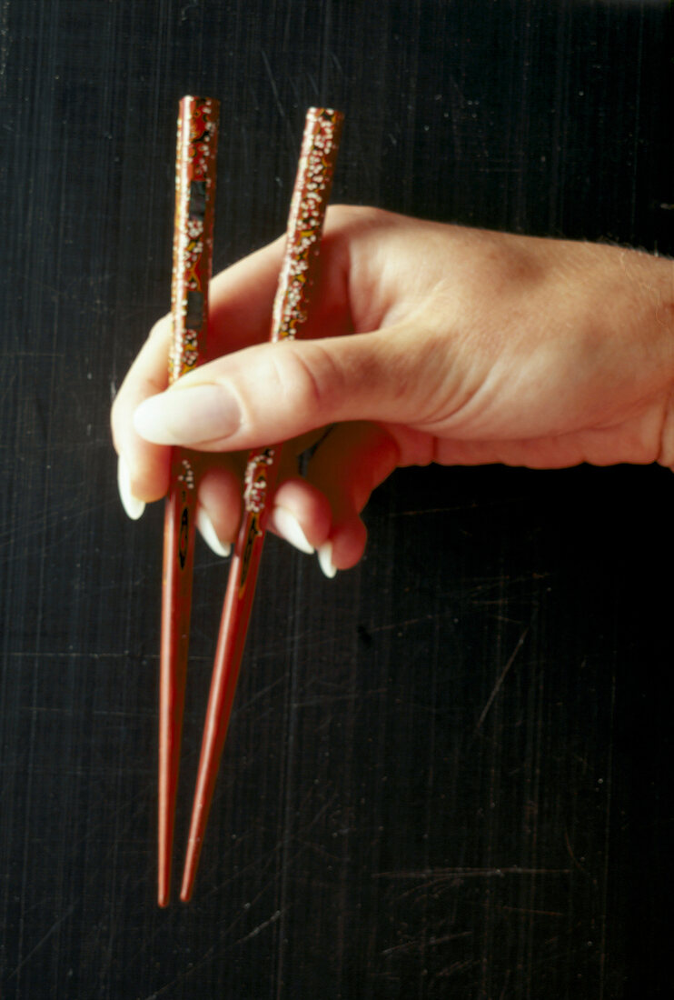 Close-up of woman's hands holding chopsticks
