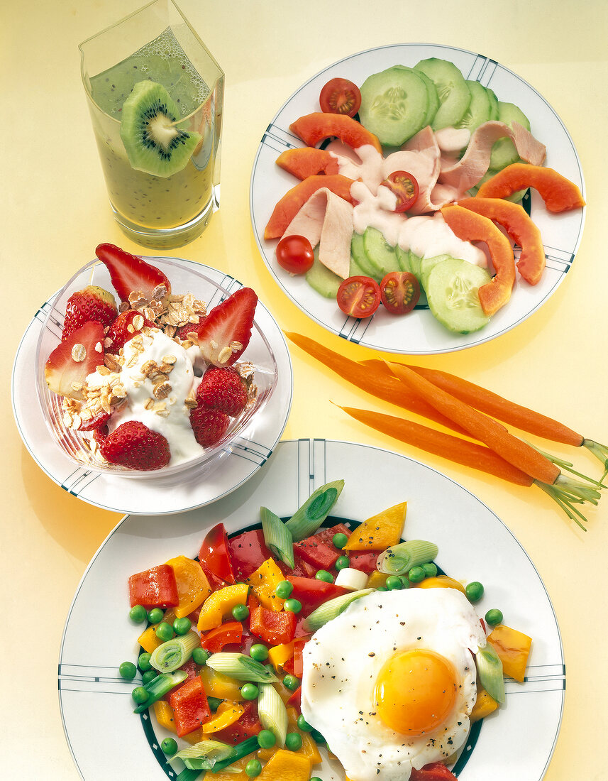 Fried eggs with stir-fry vegetables, salad, cereal, carrots and kiwi juice in plate