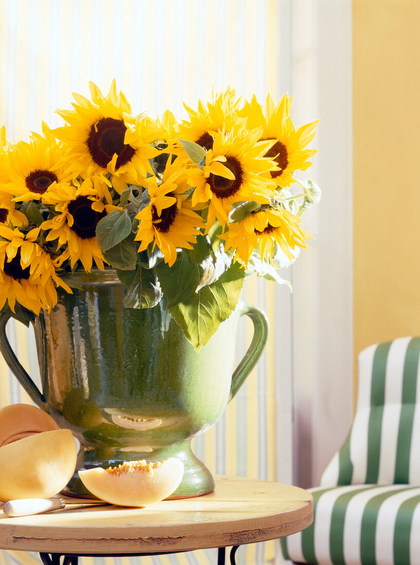 Close-up of green vase with sunflower bouquet on round table