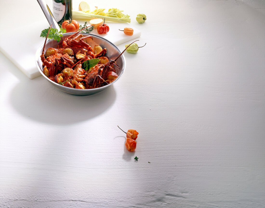 Lobster a la with chillies and tomato in pan on white background