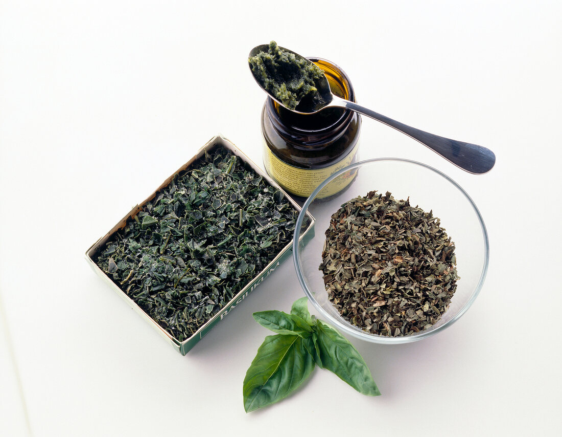 Dried frozen herbs with canned oil and basil against white background