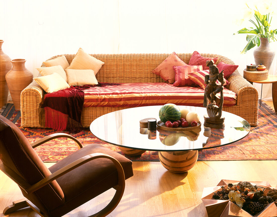 Room with wicker sofa, striped cushion, glass table and fruit basket