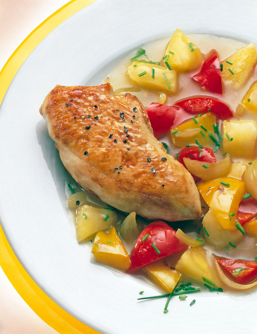 Close-up of fried chicken breast with peppers and pineapple gravy on plate