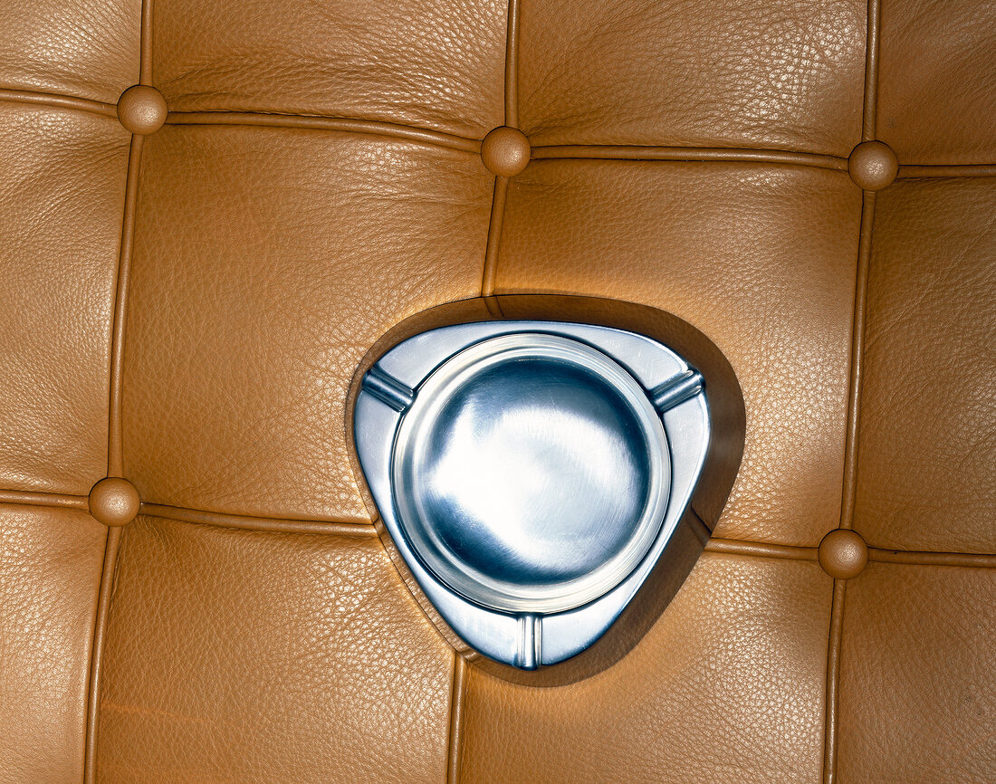 Close-up of silver ashtray against brown leather background