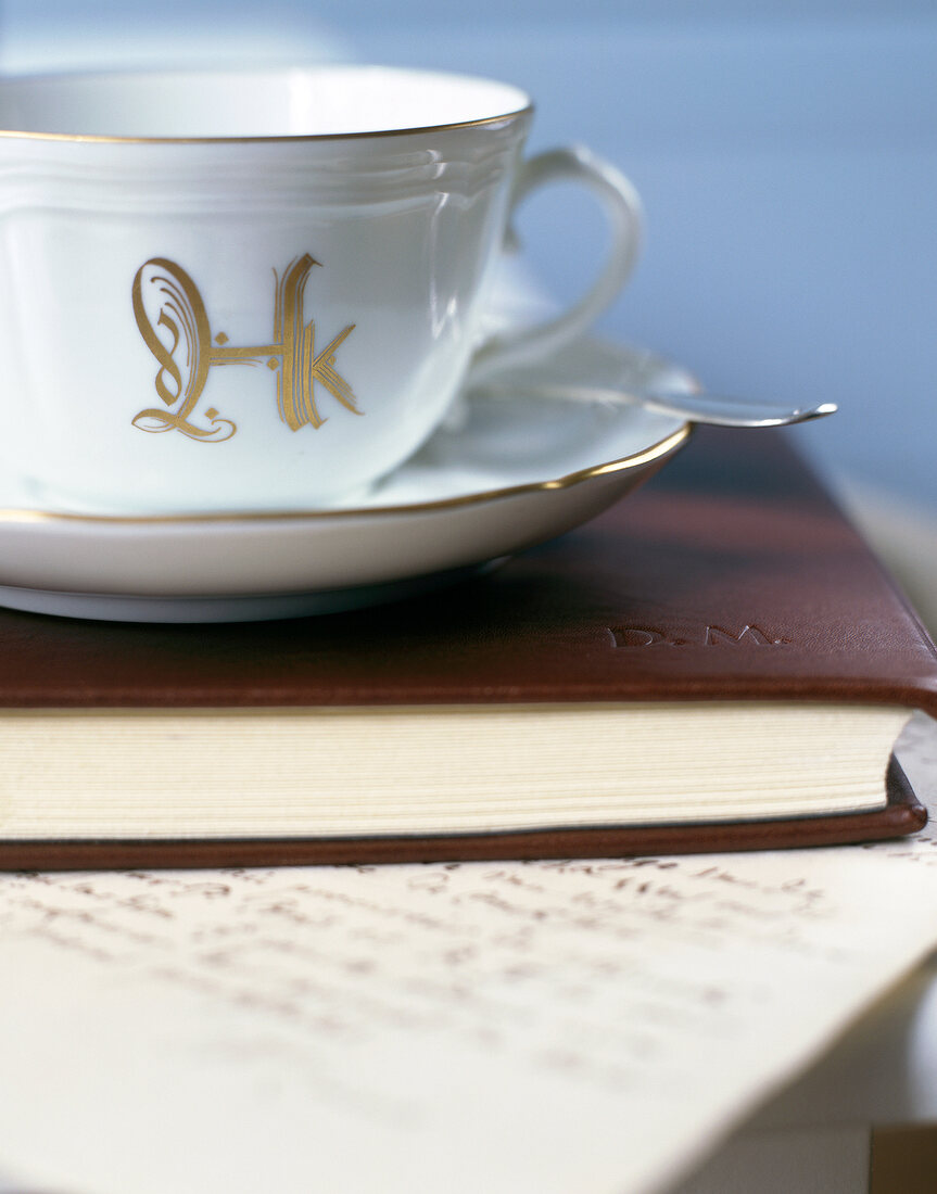 Close-up of white coffee cup with golden printed letters on book