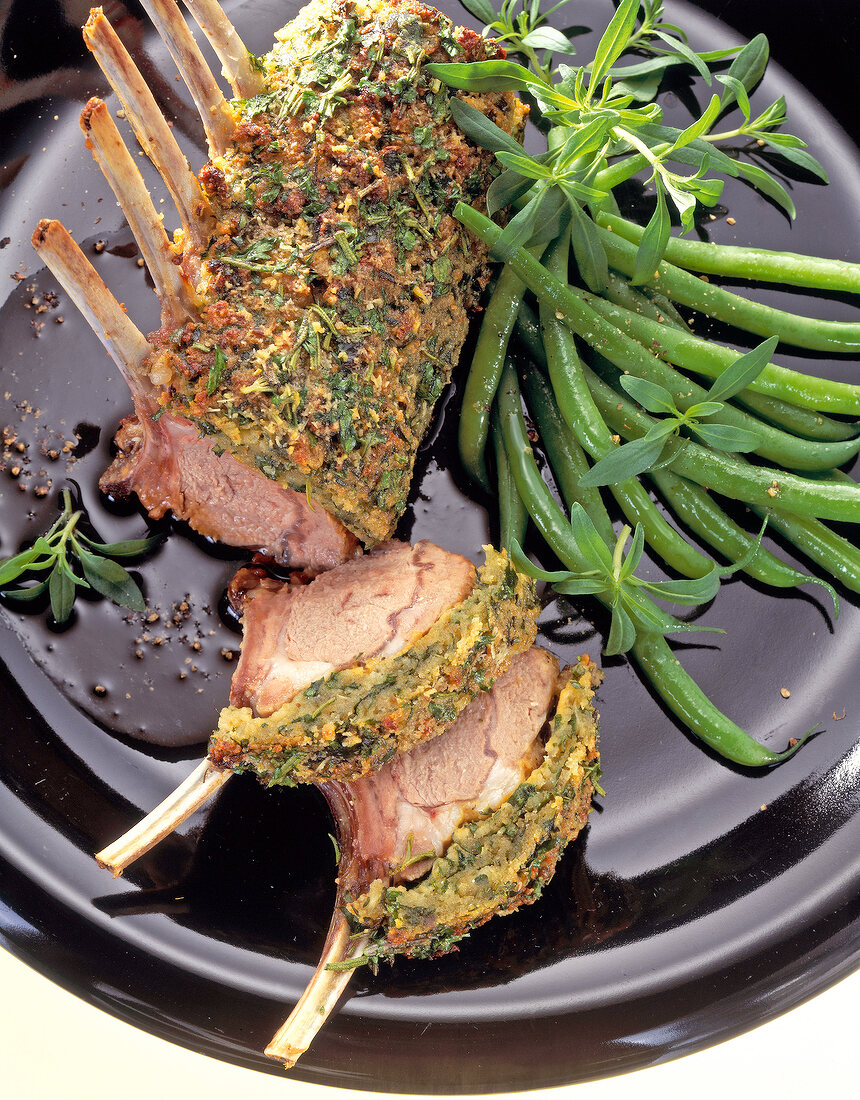 Close-up of rack of lamb with herb crust and beans on plate