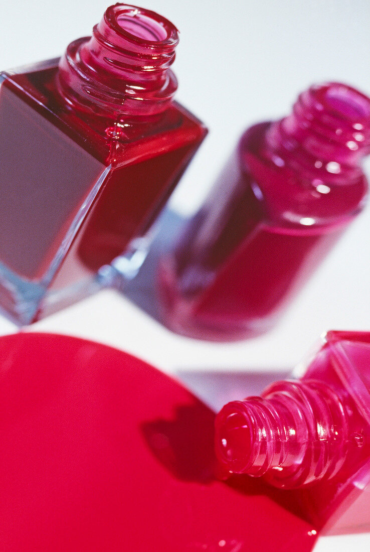 Close-up of three red and pink nail polish bottles